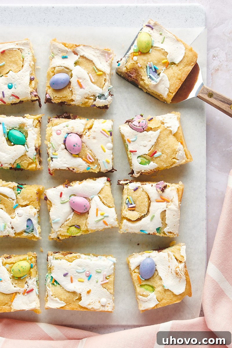 overhead view of sliced M&M Marshmallow Sugar Cookie Bars on white parchment paper, showcasing the vibrant M&Ms and gooey marshmallow layer
