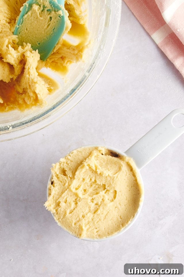 overhead view of a portion of cookie dough reserved in a measuring cup, to be used for the topping