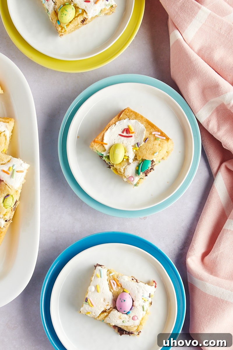 overhead view of M&M Marshmallow Sugar Cookie Bars on white plates rimmed in bright colors, ready to be served
