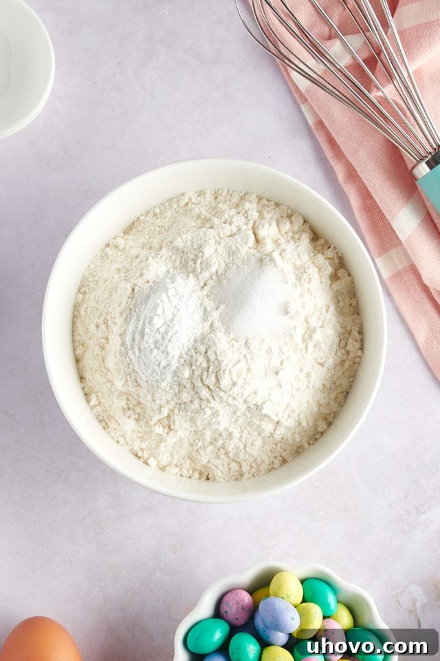 overhead view of flour, baking powder, and salt measured into a white mixing bowl