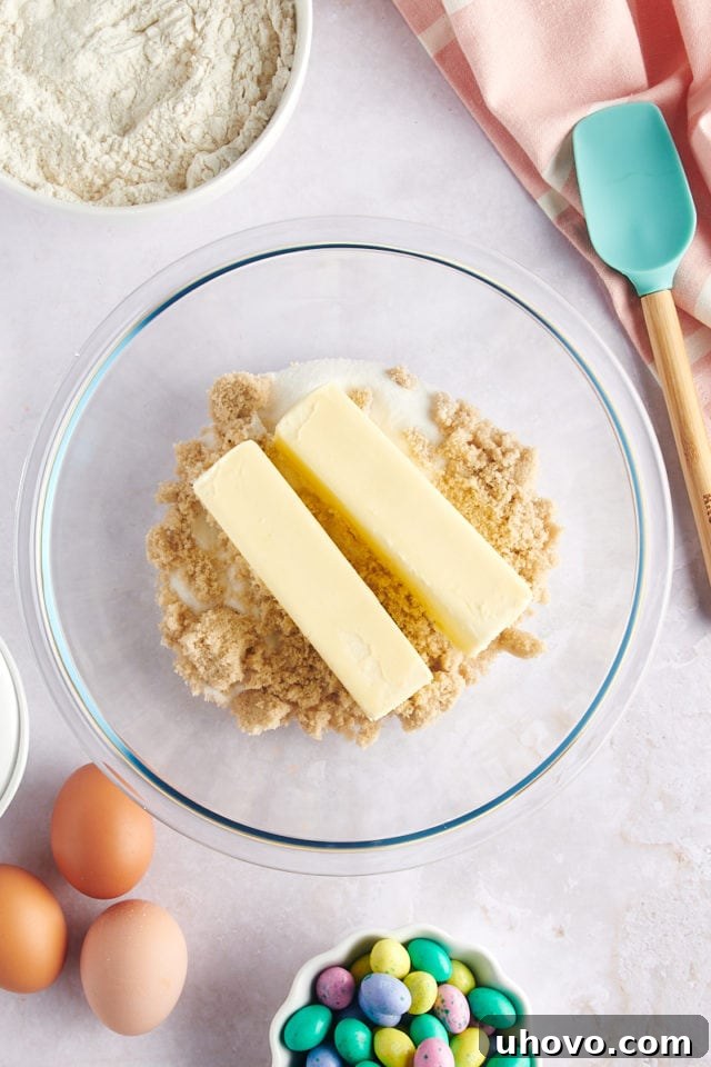 overhead view of softened butter, granulated sugar, and light brown sugar in a glass mixing bowl, ready for creaming