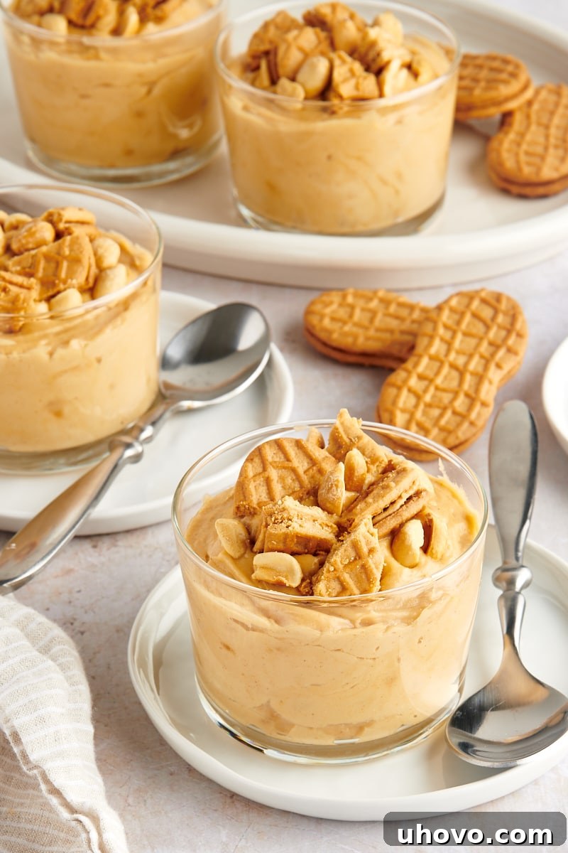 servings of Peanut Butter Mousse in clear glasses topped with peanuts and cookie pieces