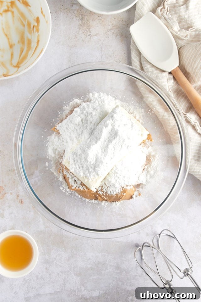 overhead view of cream cheese, peanut butter, and confectioners' sugar in a glass mixing bowl