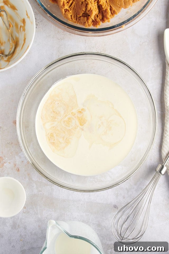 overhead view of heavy cream and vanilla extract in a glass mixing bowl