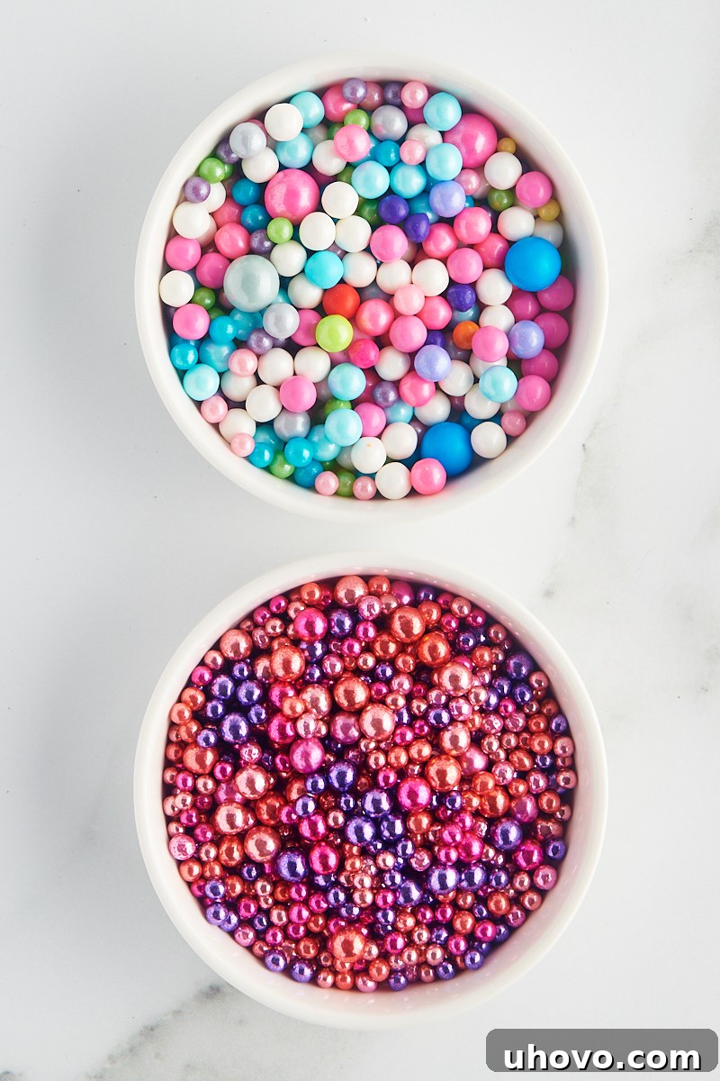 overhead view of dragées and sugar pearls in white bowls on a marble surface