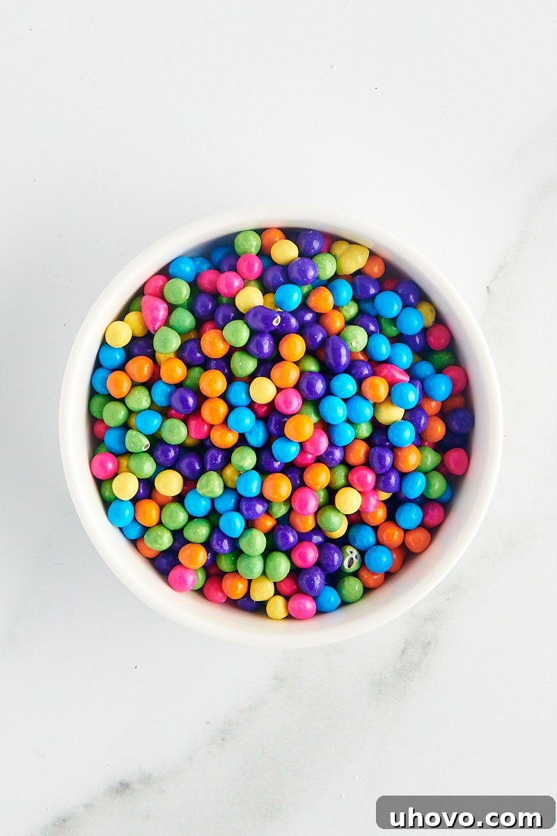 overhead view of rainbow sixlets in a white bowl on a marble surface