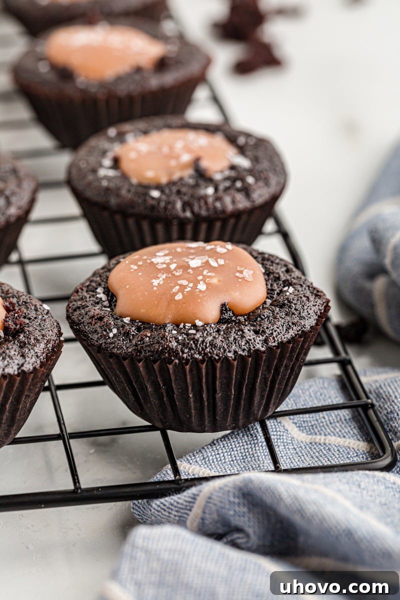 A single chocolate cupcake with its top cut open to reveal the rich, glistening salted caramel filling inside