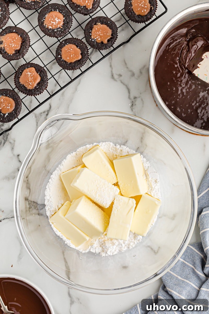 Overhead view of softened butter and sifted powdered sugar in a mixing bowl, ready to be creamed