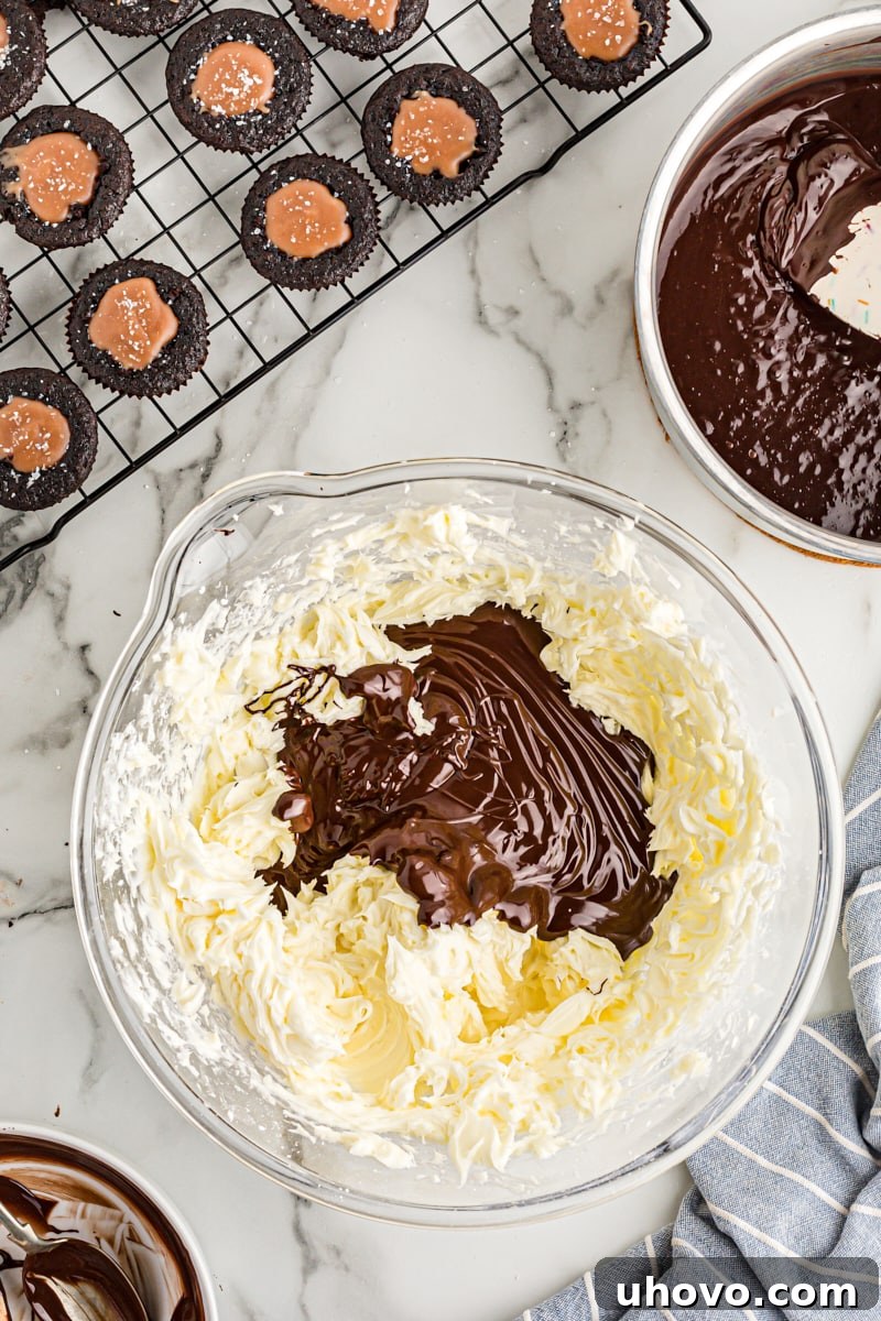 Overhead view of luxurious melted chocolate being added to the creamed butter and sugar mixture for frosting