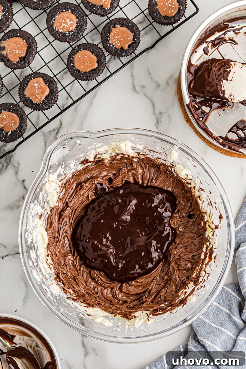 Overhead view of the melted chocolate fully incorporated into the frosting in a mixing bowl