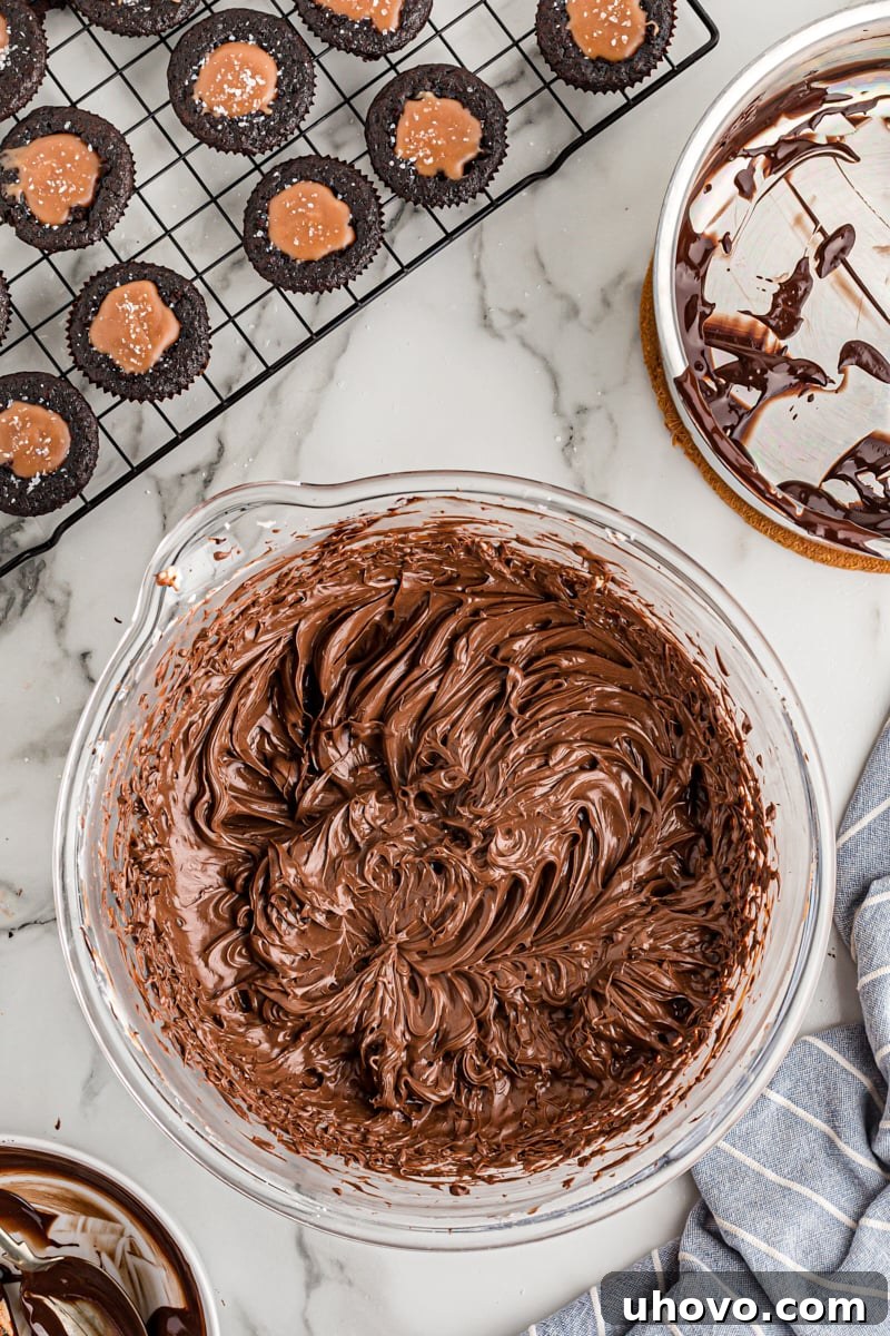 Overhead view of the finished, smooth, and glossy chocolate frosting in a mixing bowl, ready for piping
