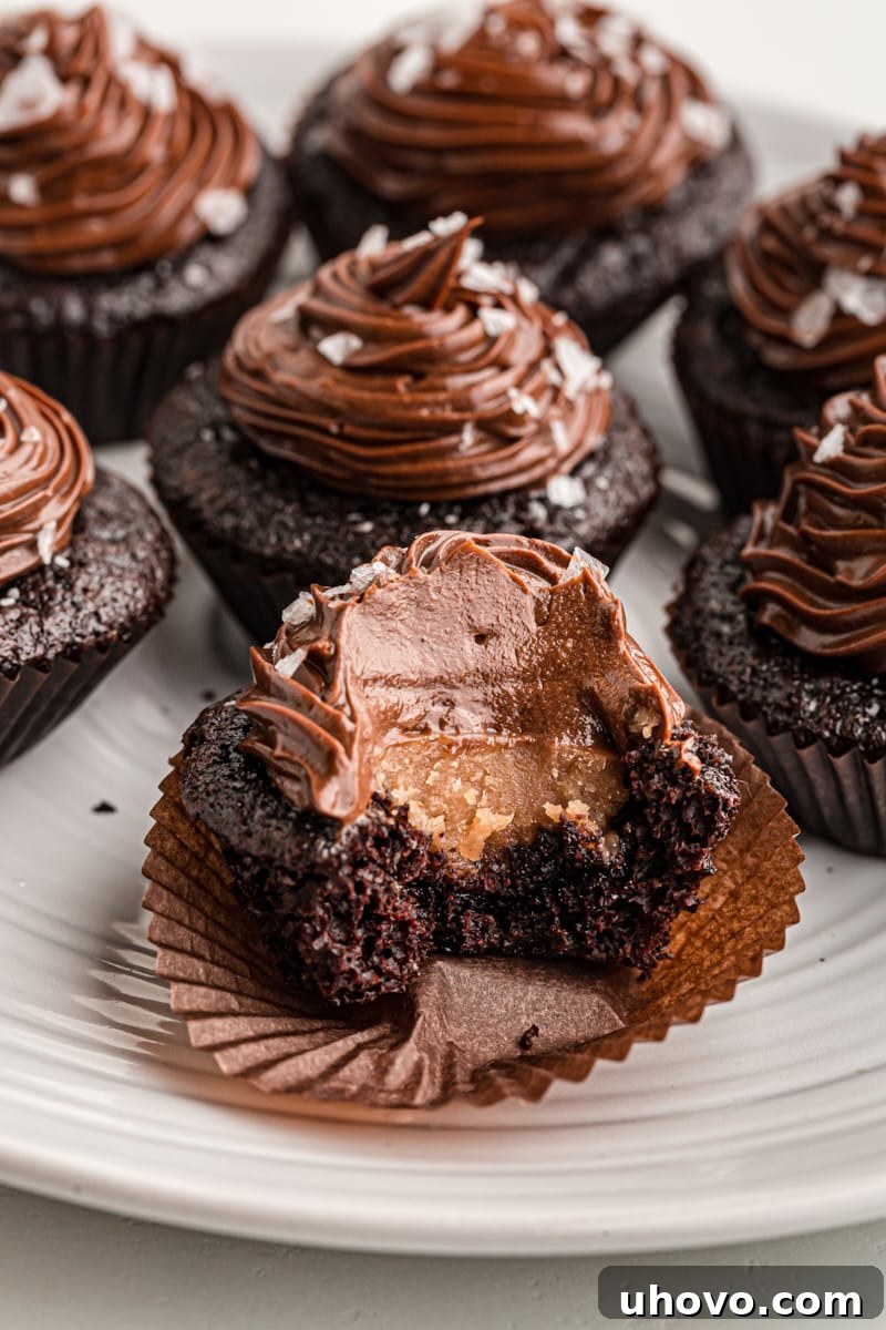 A chocolate salted caramel mini cupcake with a bite taken out, clearly revealing the luscious gooey caramel filling within