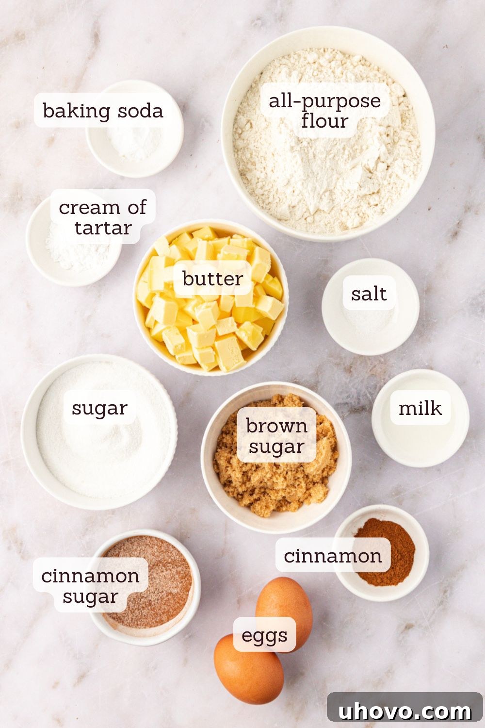 Overhead view of fresh ingredients meticulously laid out for brown butter snickerdoodles, including cubes of butter, flour, spices, eggs, milk, and sugars.