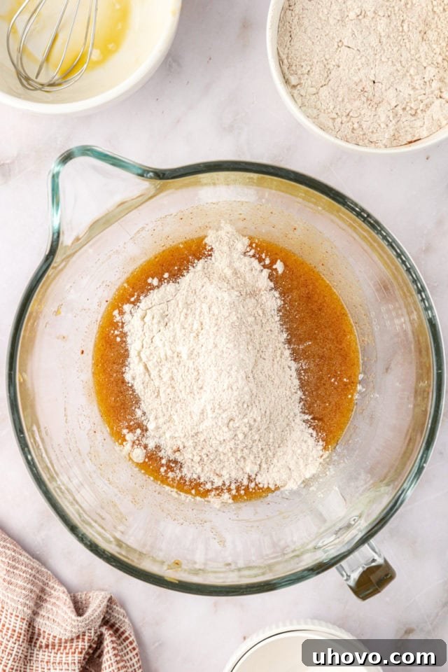 The dry ingredients (flour, cream of tartar, spices) being gently folded into the wet ingredients (browned butter, sugars, eggs, milk) for brown butter snickerdoodles.