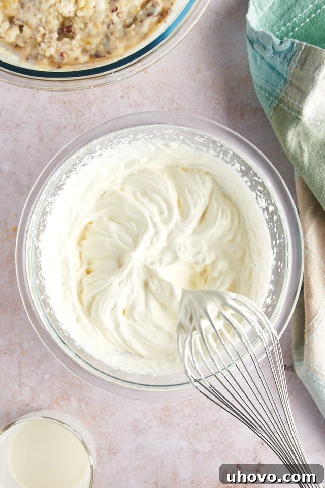 Overhead view of whipped cream in glass bowl with whisk