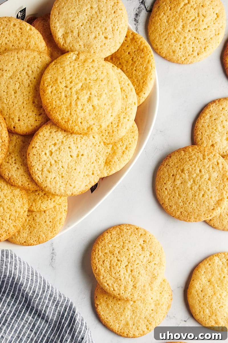 Overhead view of Southern tea cakes beautifully arranged on an oval tray and scattered on a marble surface.