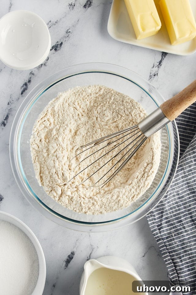 Overhead view of the whisked dry ingredients (flour, baking powder, baking soda, and salt) in a glass mixing bowl, thoroughly combined.