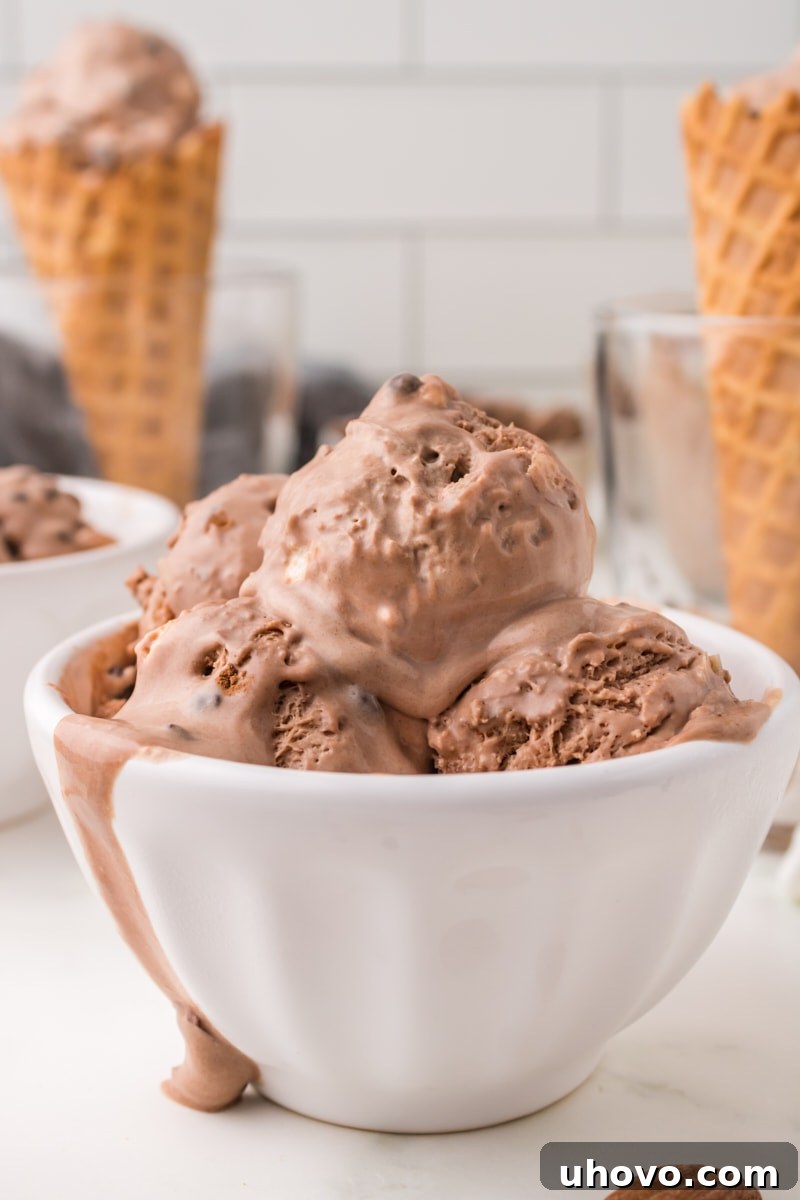 Several scoops of creamy, homemade Rocky Road Ice Cream in a pristine white bowl, showcasing the rich chocolate, fluffy marshmallows, and crunchy almonds.