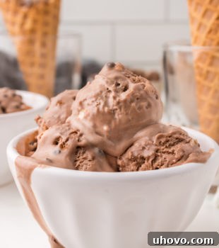 Several scoops of creamy, homemade Rocky Road Ice Cream in a pristine white bowl, showcasing the rich chocolate, fluffy marshmallows, and crunchy almonds.