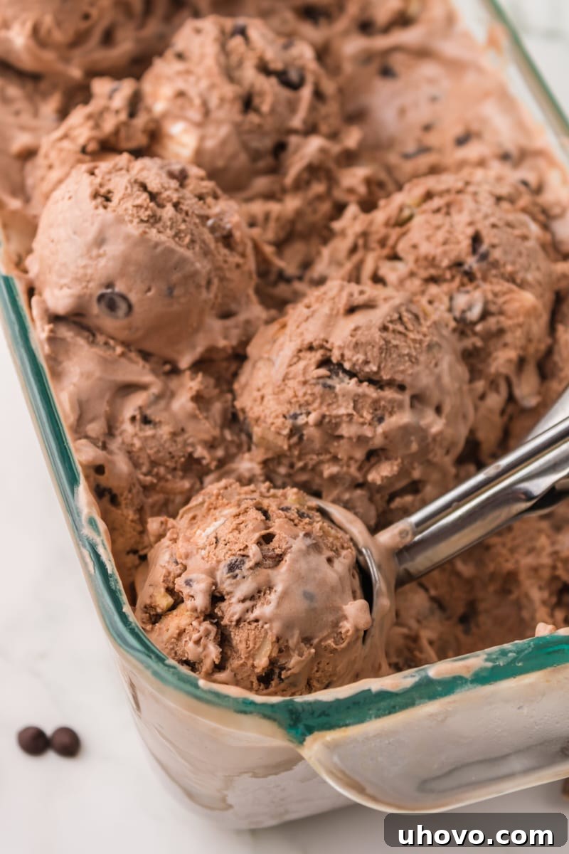 Several scoops of delectable Rocky Road Ice Cream sit perfectly in a large glass pan, ready to be dished out and enjoyed.