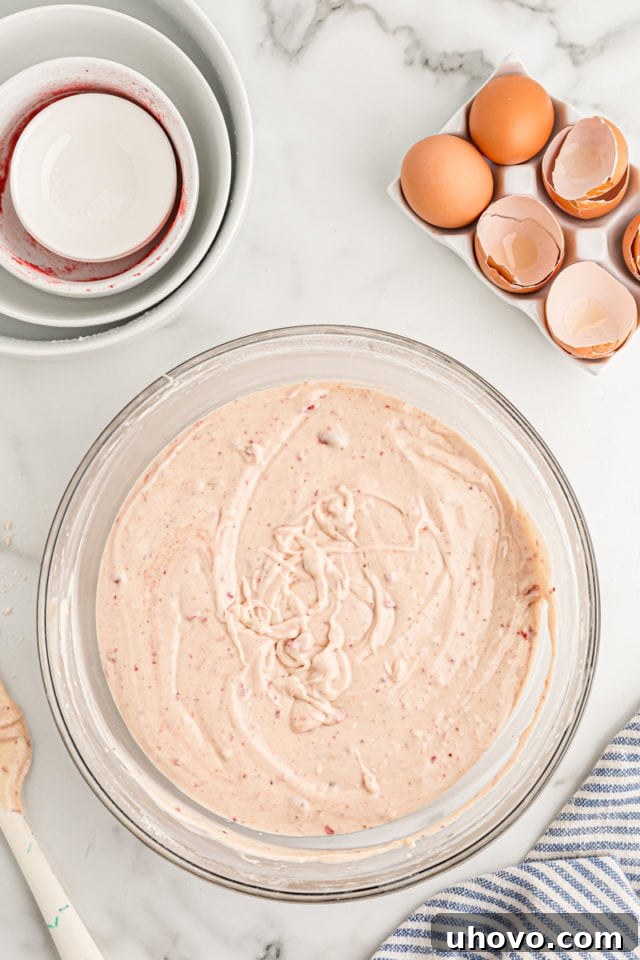 Overhead view of the fully mixed strawberry cake batter in a mixing bowl, smooth and ready for the cake pans.