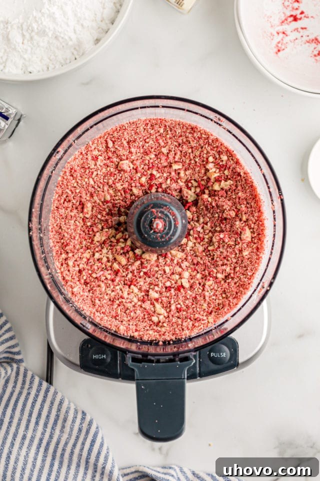 Overhead view of the strawberry crunch mixture in a food processor, after being pulsed into coarse crumbs.