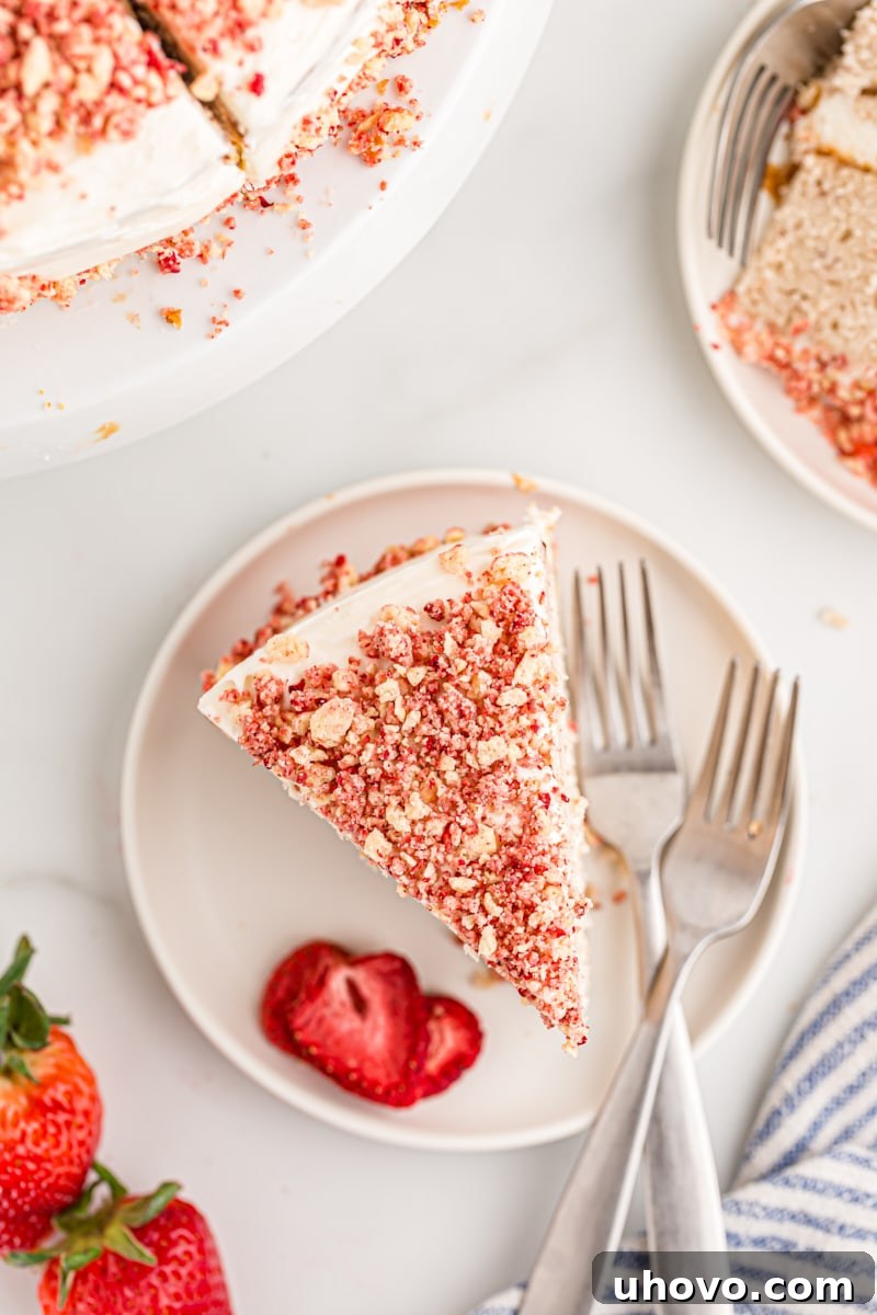 Overhead view of a single slice of strawberry crunch cake on a white plate, highlighting the detailed texture and layers.