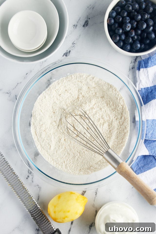A close-up, overhead view of the combined dry ingredients for blueberry scones in a glass mixing bowl, perfectly whisked and ready for the next step.
