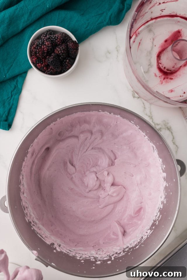 overhead view of mixed blackberry ice cream batter in a metal mixing bowl, showing a beautiful pink hue