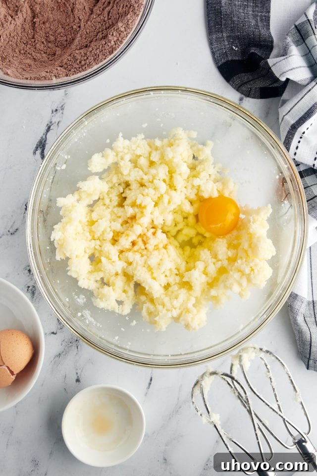 overhead view of egg and vanilla added to creamed butter and sugar in a glass mixing bowl