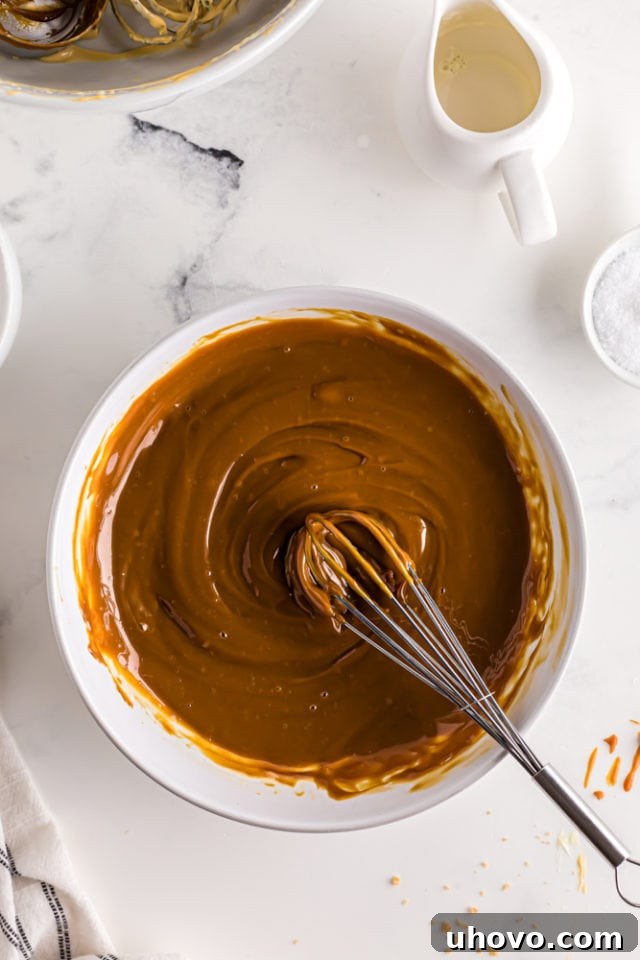 Overhead view of the glossy dulce de leche glaze in a white mixing bowl, perfectly smooth and ready to be poured.