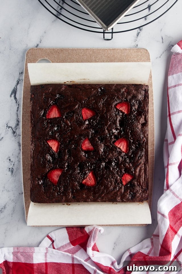 Overhead view of the cooled strawberry brownies on a cutting board, before being sliced into individual squares.