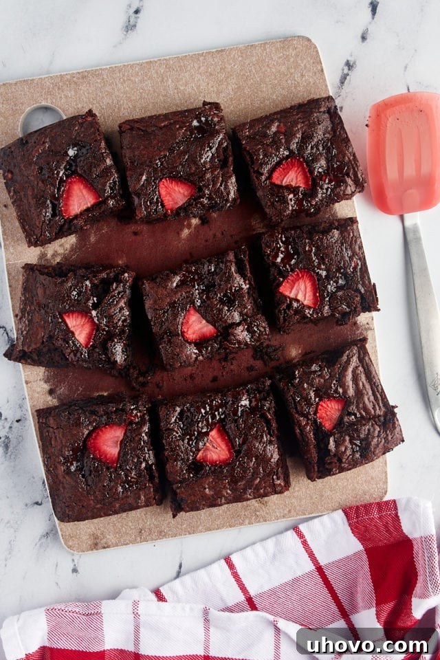 Overhead view of sliced strawberry brownies arranged on a cutting board, revealing their fudgy interior and berry swirls.