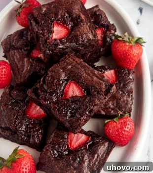 Overhead view of strawberry brownies on a platter with fresh berries.