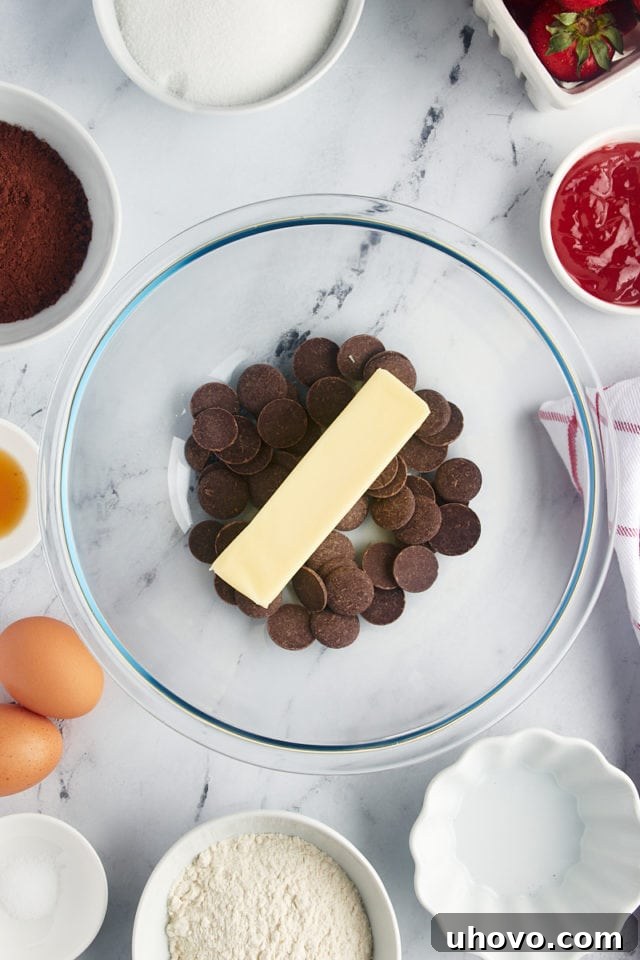 Overhead view of butter and dark chocolate discs in a mixing bowl before melting.