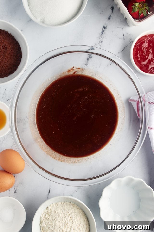Overhead view of melted chocolate and butter in a mixing bowl after being stirred until smooth and glossy.