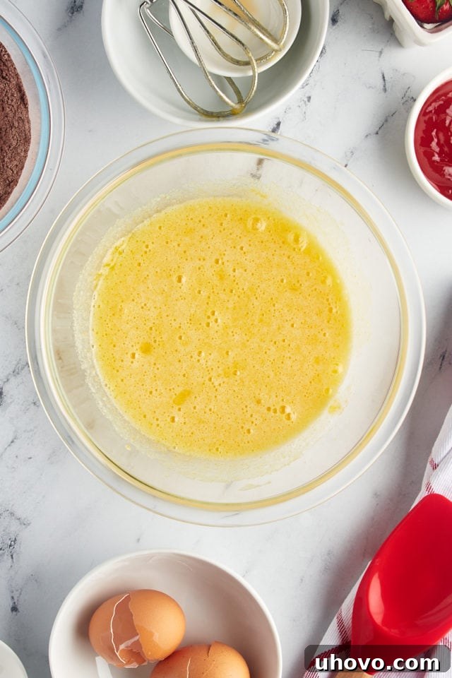 Overhead view of the thoroughly beaten egg, sugar, and vanilla mixture in a bowl, light and airy.