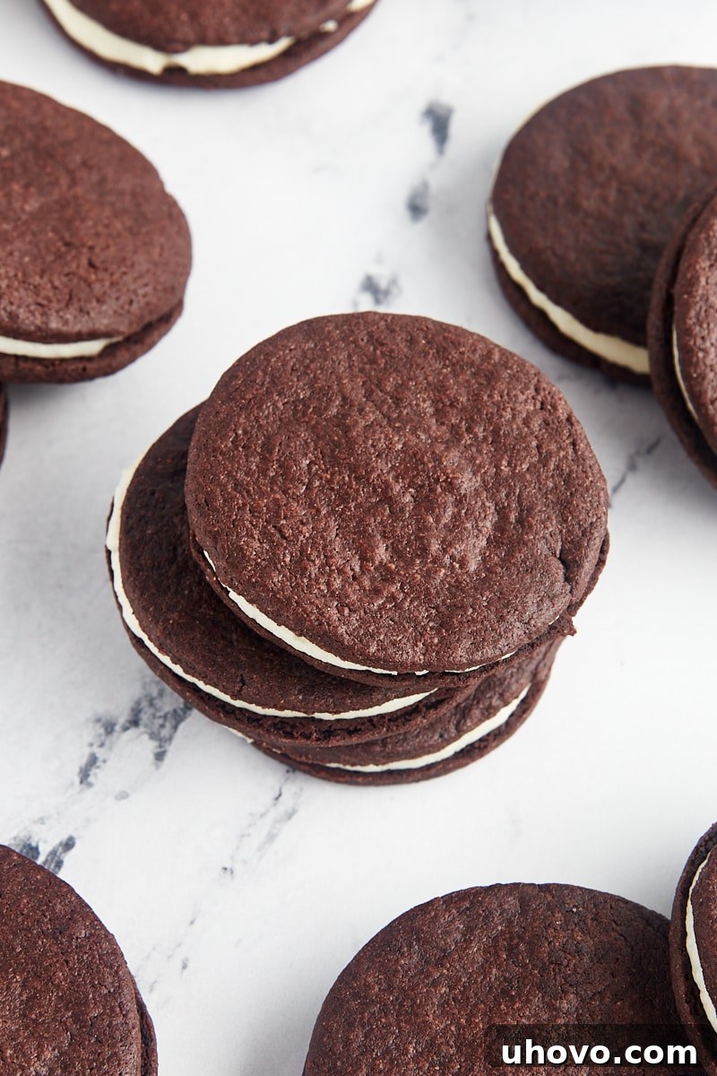 A charming stack of three homemade Oreos, artfully arranged on a clean surface with more delicious cookies scattered around, highlighting their inviting appeal.