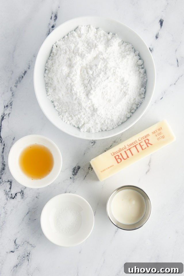 Overhead view of the ingredients for the creamy vanilla buttercream frosting: butter, confectioners' sugar, heavy cream, and vanilla extract.