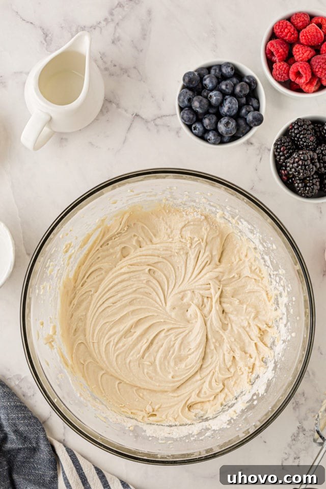 A comprehensive overhead view of the perfectly mixed cupcake batter in a glass mixing bowl, smooth and ready for the addition of berries.