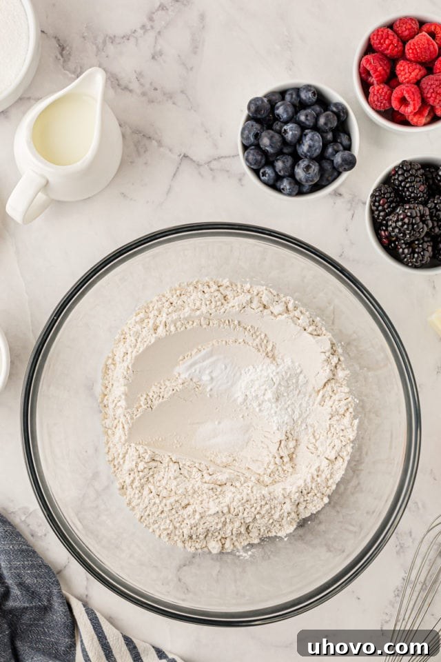 An overhead shot of a glass mixing bowl containing all-purpose flour, baking powder, baking soda, and salt, ready to be whisked together for the cupcake batter.