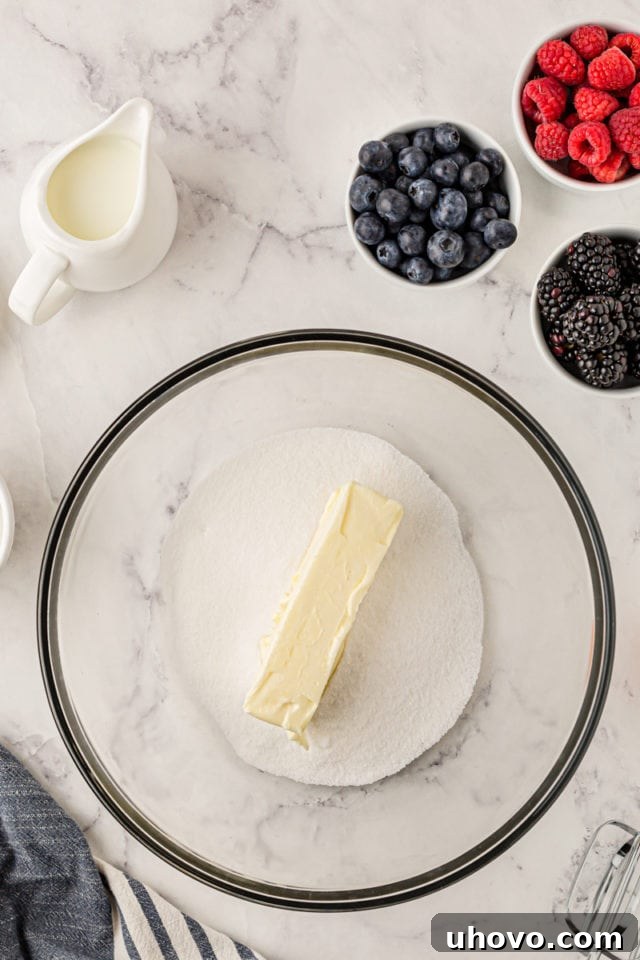 An overhead view of softened butter and granulated sugar being creamed together in a glass mixing bowl, a crucial step for light and fluffy cupcakes.