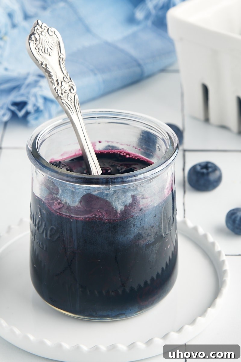 A glass jar filled with luscious blueberry compote, with a spoon resting inside, ready to be enjoyed.