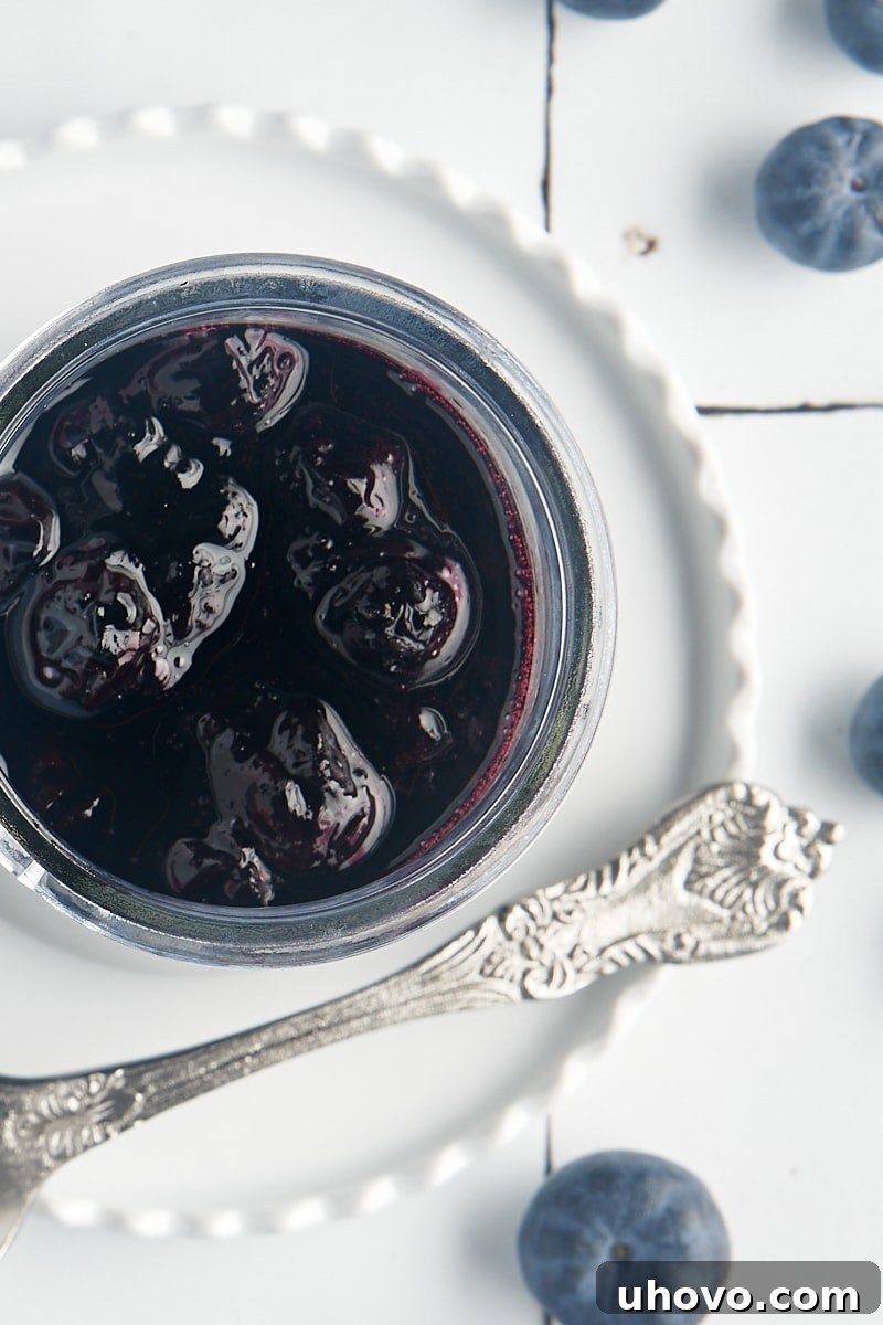 An overhead shot of vibrant blueberry compote served in a clear glass jar, showcasing its rich color and inviting texture.