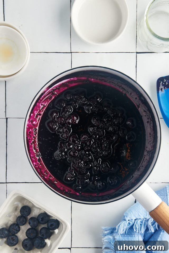 A close-up overhead view of the finished blueberry compote resting in a white saucepan after cooking, showcasing its rich texture and color.