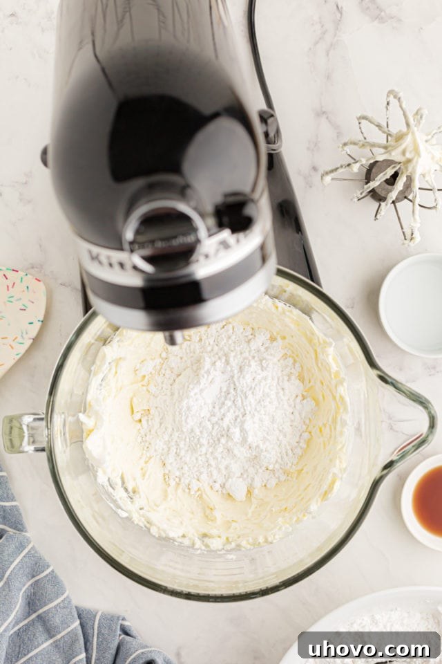 overhead view of confectioners sugar added to creamed butter and shortening