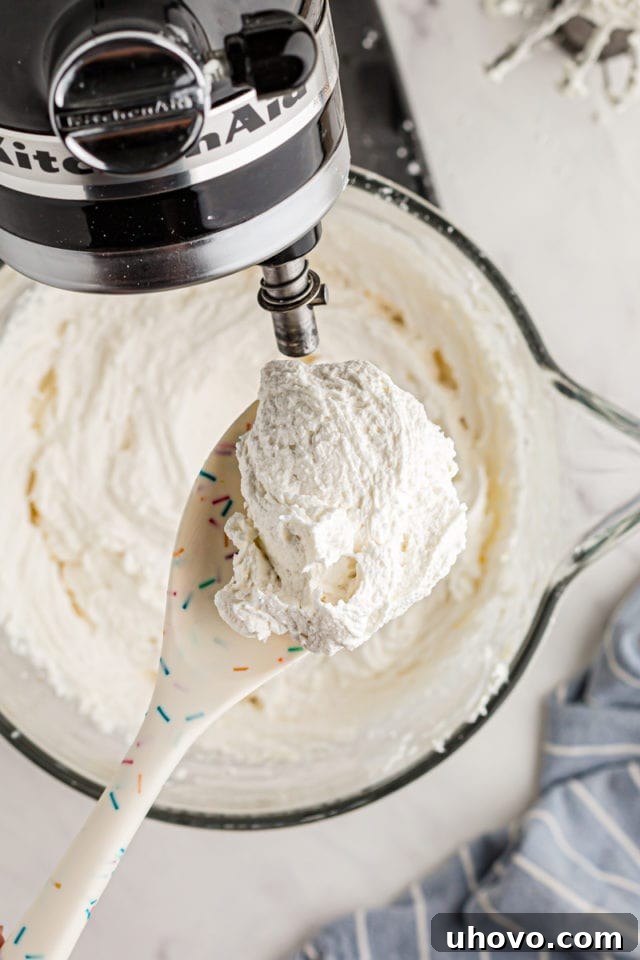 overhead view of a spoonful of vanilla buttercream with the remaining frosting in the bowl of a stand mixer in the background