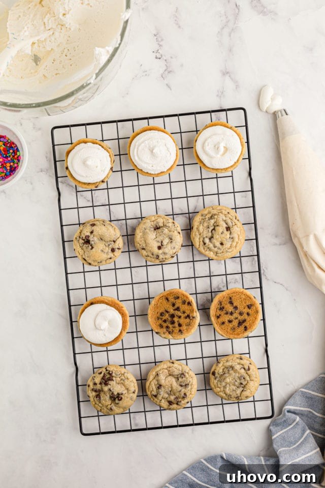 overhead view of chocolate chip cookies on a wire rack, with frosting piped onto the bottoms of some of the cookies