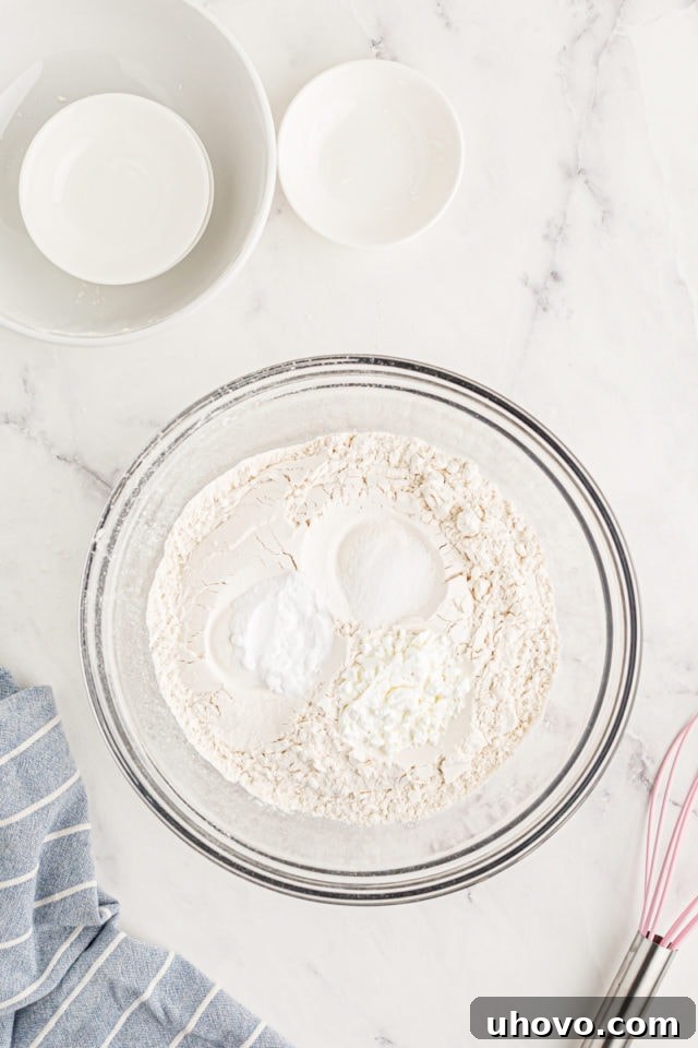 overhead view of flour, cornstarch, baking soda, and salt in a glass mixing bowl