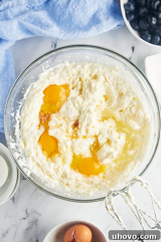 overhead view of eggs and vanilla added to cheesecake batter